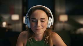 Pleased woman listening headphones at dark place. Positive freelancer dancing rejoicing music at modern flat closeup. Successful girl drinking coffee at night apartments. People emotions concept - Powered by Shutterstock - Get 15% off with code: PIKWIZARD15