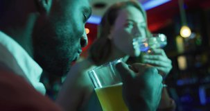 Video of diverse group of happy friends drinking and laughing at a nightclub bar. Friendship, going out and socialising concept.