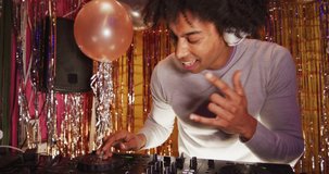 Video of happy african american male dj playing music, dancing and making faces at a nightclub. Fun, inclusivity, going out and party concept.
