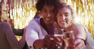 Video of happy diverse couple dancing holding glasses of champagne at a nightclub. Fun, drinking, going out and party concept.