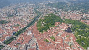 Inscription on video. Graz, Austria. The historic city center aerial view. Mount Schlossberg (Castle Hill). Multicolored text appears and disappears, Aerial View, Departure of the camera