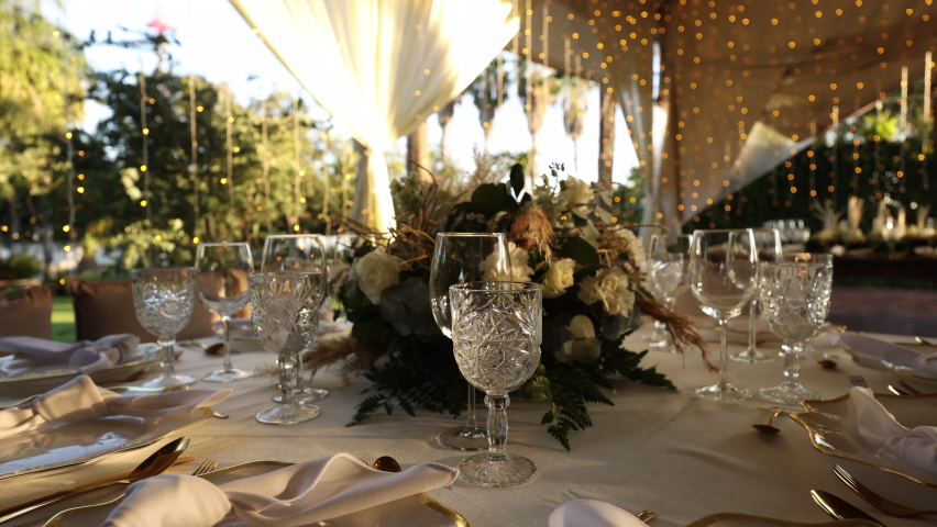 Round table decoration elegant tableware with beautiful sunset behind. Detailed view of the wedding reception within tropical natural environment around. High quality 4k footage | Shutterstock HD Video #1096871729