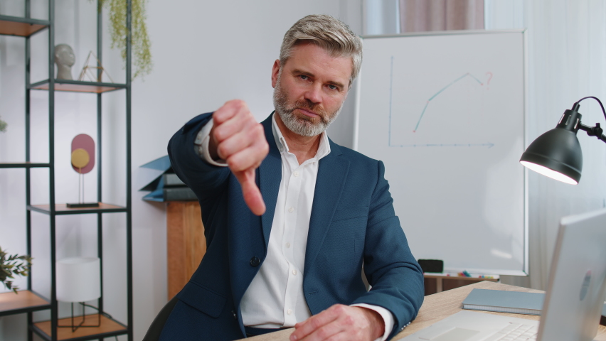 Dislike. Upset mature businessman working on laptop computer at home office thumbs down sign gesture, expressing discontent, disapproval, dissatisfied bad work. Displeased serious freelancer old man | Shutterstock HD Video #1096872691