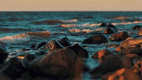 Dark sea water in autumn. Rocky coast of the Pacific Ocean, waves of sea water crashing on the rocks. Dramatic sunset nature. Selective soft focus for video