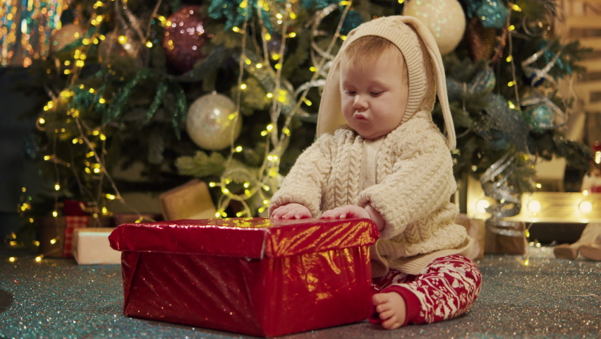 Portrait sweet little asian baby boy at background of decorated fir-tree open red wrapped box with surprise of Christmas. Happy cute kid unpack present or gift. Merry xmas, happy new year love concept Royalty-Free Stock Footage #1096874029