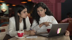 Two Indian girls meeting, brainstorming and discussing about strategy marketing and financial plan at small business.Asian Business women siting and communicating while  working on laptop,in the cafe.