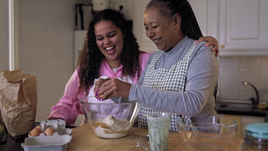 Happy African mother and daughter preparing a homemade dessert