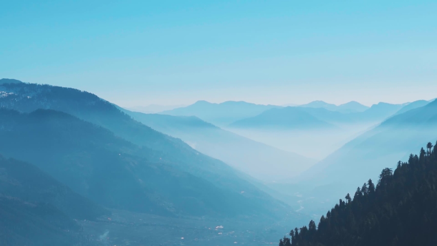 Foggy mountain layers as seen from above the mountains during the Rani Sui Trek near Manali in Himachal Pradesh, India. Natural mountain background. Himalayas covered by the fog during the morning.  | Shutterstock HD Video #1096880835