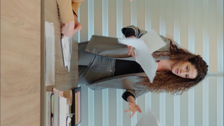 Vertical Screen: Workplace bullying business woman unsatisfied with work throwing papers and pointing with her fingers. Team work trouble. | Shutterstock HD Video #1096882213