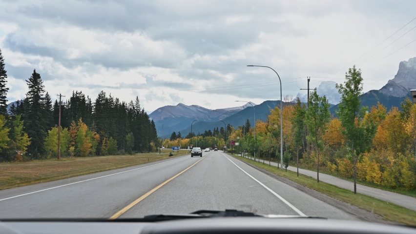 Road trip of car driving on highway road with rocky mountains in autumn forest at Banff national park, Canada