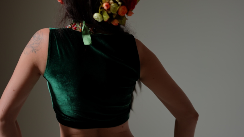 Back view unrecognizable graceful woman turning shaking hips in slow motion. caucasian belly dancer performing Middle Eastern dance at grey background