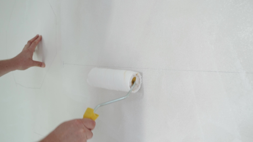 Construction worker hand painting the ceiling inside the house and building. Repairman using with white paint roller on the construction site. | Shutterstock HD Video #1096890521