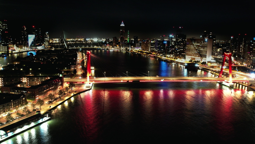 Aerials shots of the city center of Rotterdam at night. Erasmusbrug, Willemsbrug, The Hef, Central Train Station and passing boats over the river Meuse. 