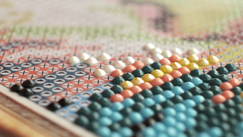 Diamond mosaic painting fragment of making close-up, handmade hobby. performing long monotonous, monotonous movements, you unconsciously do natural meditation.
