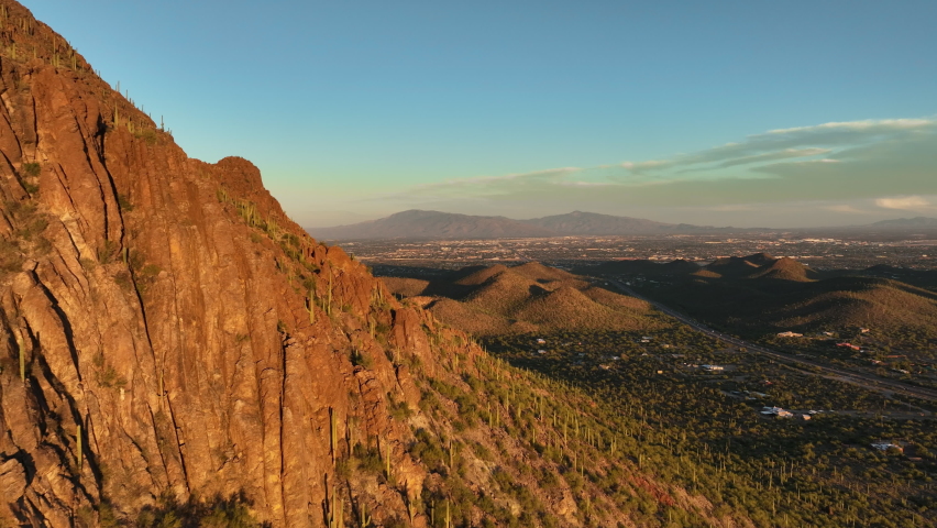 Drone shot passing rocky peaks of desert mountains revealing Tucson Arizona, POV aerial Royalty-Free Stock Footage #1096895793