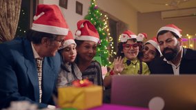 Happy smiling modern Asian Indian family members wearing Santa caps interacting or talking online with distant relatives on a laptop during Christmas eve holidays. celebration, connectivity concept. - Powered by Shutterstock - Get 15% off with code: PIKWIZARD15