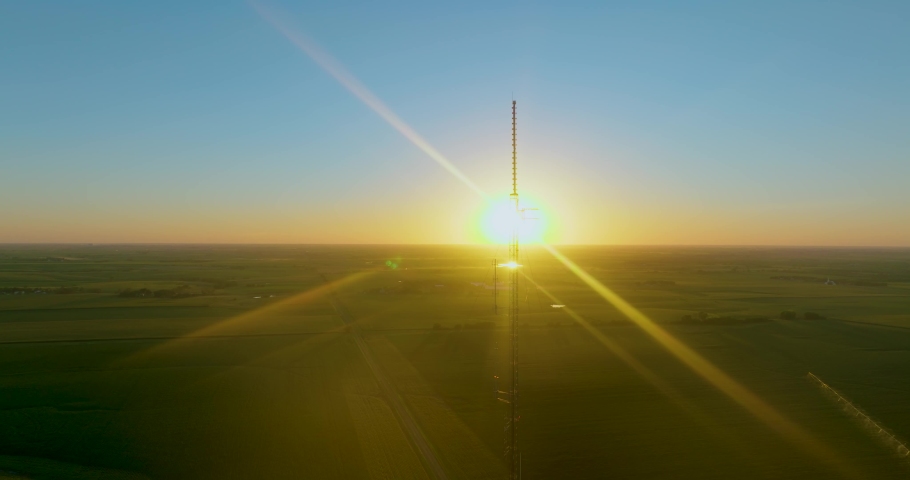 The sun can be seen setting right behind a tower. The camera moves down. The suns rays are vibrant.