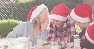 Animation of christmas greetings text over caucasian family in santa hats at christmas table. Christmas, festivity, celebration and tradition concept digitally generated video.