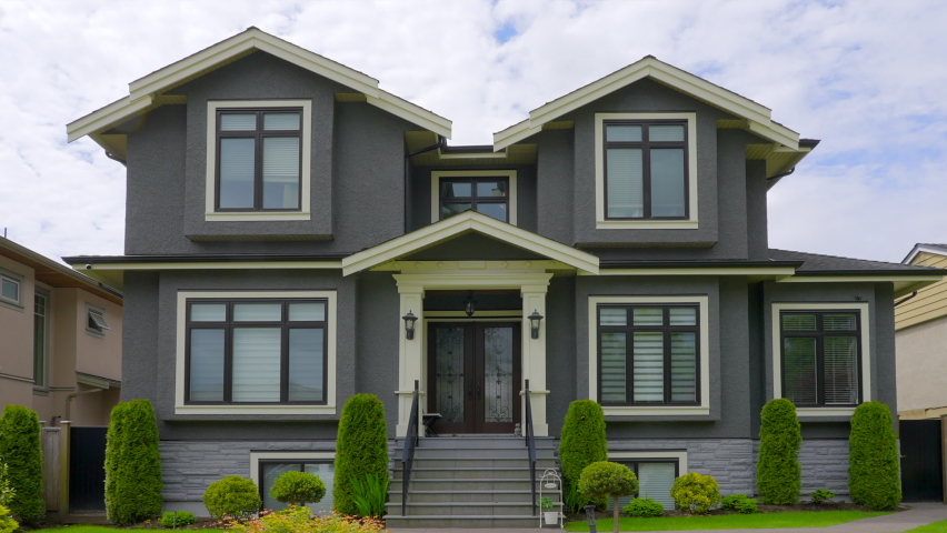 Establishing shot of two story stucco luxury house with garage door, big tree and nice spring blossom landscape in Vancouver, Canada, North America. Day time on May 2022. ProRes 422 HQ.
