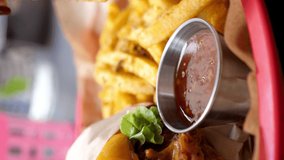a woman's hand dips french fries in a sauce in slow motion