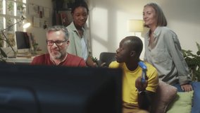 Group of joyous multiethnic friends playing video game together on TV while gathering at home