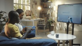African American couple sitting on sofa in living room and playing shooter video game on TV - Powered by Shutterstock - Get 15% off with code: PIKWIZARD15
