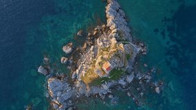 Slowmotion aerial video. The Sveta Nedelja - Christian church on a tiny island in the sea close to the city of Petrovac Lots of martlets fly over the island