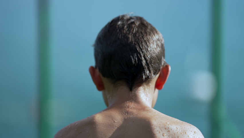 Blurred of teen young boy running by lake dock and plunging into water in slow motion. Child dive in water