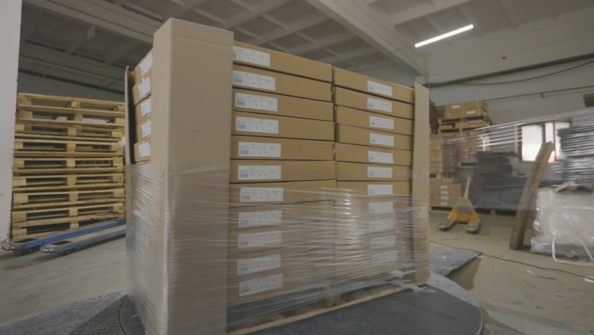 Packaging boxes with products in plastic film at the factory. A special machine wraps boxes in polyethylene film Royalty-Free Stock Footage #1096927125