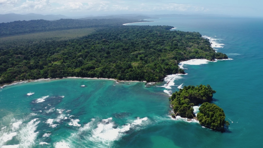 Aerial view showing tropical island with dense forest and turquoise Caribbean Sea in foreground during summer - Costa Rica, Puerto Viejo