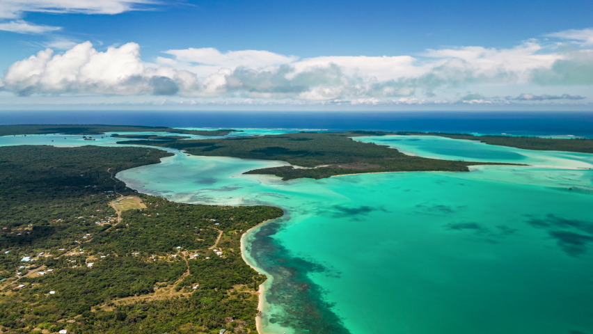 Clouds drift in the sky casting shadows on Saint Maurice Bay and Saint Joseph Bay in the Isle of Pines - aerial hyper lapse