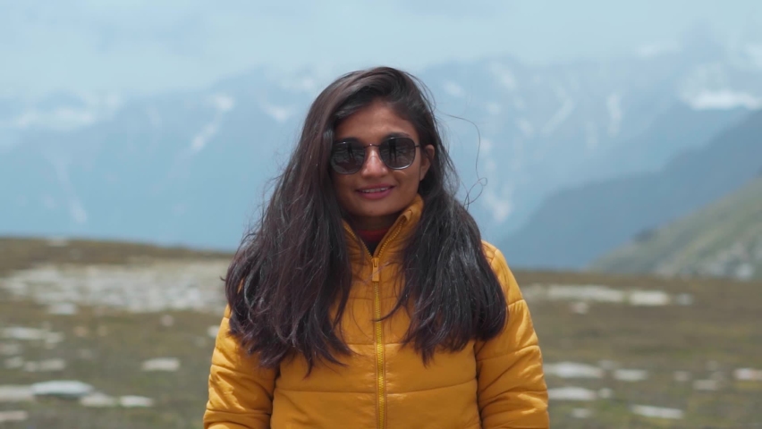 Portrait of teenager Indian girl tourist with sunglasses looking at snow covered mountains in Manali, Himachal Pradesh, India. Travel lifestyle. Female travel influencer enjoying vacation in mountains | Shutterstock HD Video #1096932457