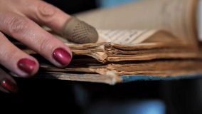 worn pages of an ancient book
woman with a beautiful manicure in a special fingernail turns pages of old book close up