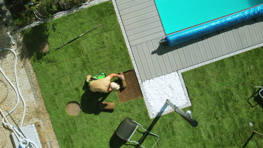Professional Landscaper Replacing Naturel Grass Turfs Along Outdoor Residential Swimming Pool. Aerial View., an Industrial Video by Virrage Images