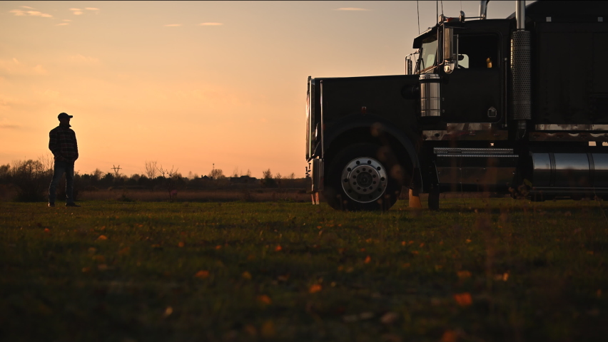 Semi Truck Driver in Front of His Vehicle During Scenic Countryside Sunset. Transportation Industry Theme. Royalty-Free Stock Footage #1096939083
