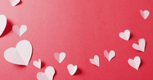 Video of folded white paper hearts, on red background with copy space. Valentine's day, romance, love and celebration concept.