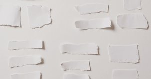 Video of close up of multiple torn pieces of paper on white background. Paper, writing, texture and materials concept.