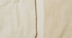 Video of close up of torn pieces cream paper on white background. Paper, writing, texture and materials concept.