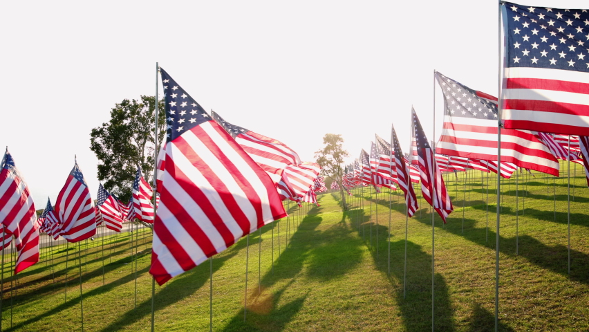 View on American USA flags waving in the wind against sunset in nature outdoor background. Concept of 4th of July, Memorial Day, Independence Day, September 09,11,2001. High quality 4k footage Royalty-Free Stock Footage #1096947089