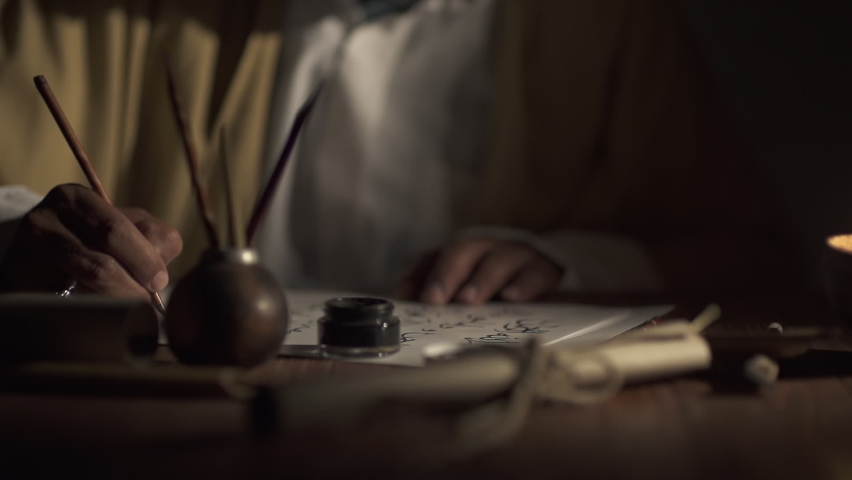 A medieval man uses an old pen with ink to write Arabic script on an a paper lit by a candle,slow motion | Shutterstock HD Video #1096953861
