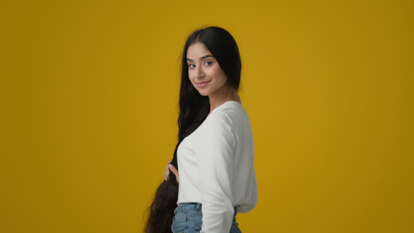 20s brunette Indian ethnic woman girl lady female with long gorgeous soft silk healthy shiny hair showing hairstyle throw flying curls satisfied with shampoo cosmetics conditioner haircare cosmetics