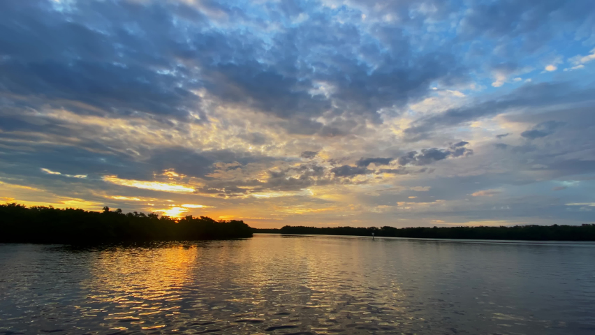 Cinematic shot of a beautiful sunrise sky over the ocean and mangrove forest at Cockroach Bay in the background