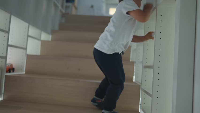 Child going up the staircases at home. One little boy climbing stairs going to the second floor of house