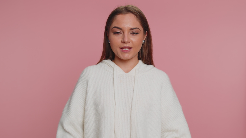 Rock n roll. Overjoyed delighted woman 20 years old in sweater showing gesture by hands, cool sign, shouting yeah with crazy expression, dancing, emotionally rejoicing in success win on pink wall