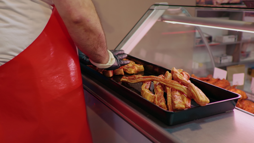 Butchers hands arranging meat on tray for display cabinet at shop. Male placing slices of meat in fulfilling tupperware. Food industry. | Shutterstock HD Video #1096971133