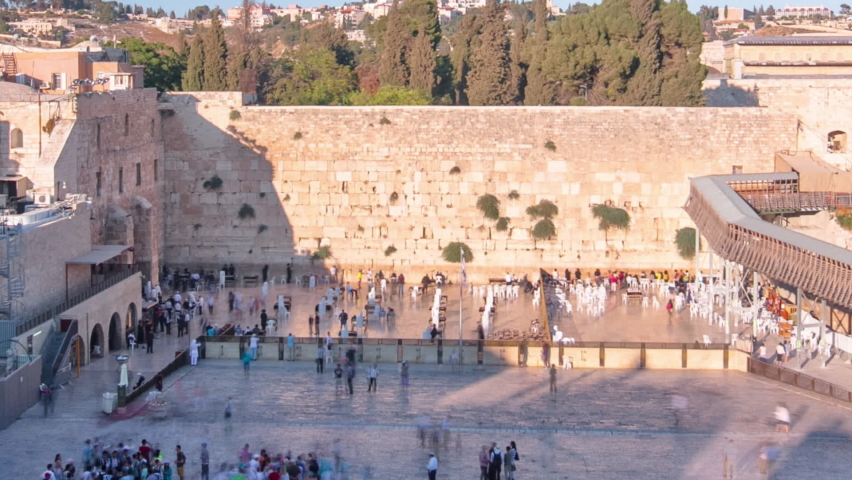 The Temple Mount in Jerusalem, including the Western Wall and the golden Dome of the Rock during Sunset timelapse. Shadow covering the wall. Many people at shabbat Royalty-Free Stock Footage #1096974663