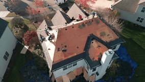 Wide Aerial footage of Roofer repair or replace shingle that has been damaged and needing replacement at sunny day. 
