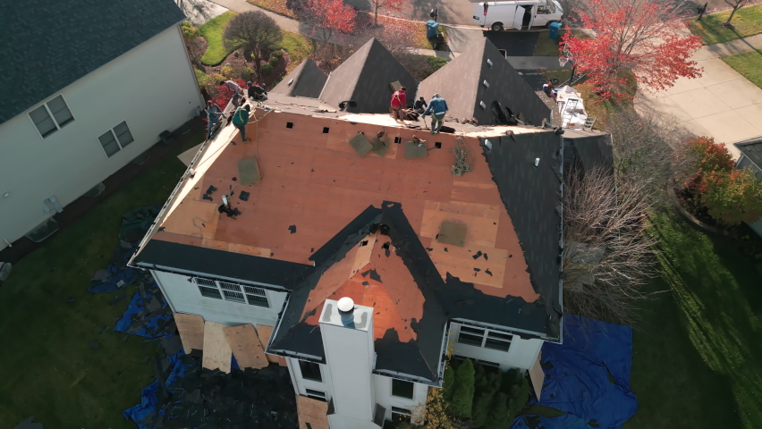 Wide Aerial footage of Roofer repair or replace shingle that has been damaged and needing replacement at sunny day.  | Shutterstock HD Video #1096979069