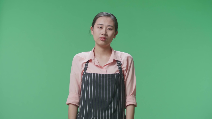 Sad Asian Female Housekeeper With An Apron Negatively Shaking Her Head And Looking Around While Standing In The Green Screen Studio
 | Shutterstock HD Video #1096979213