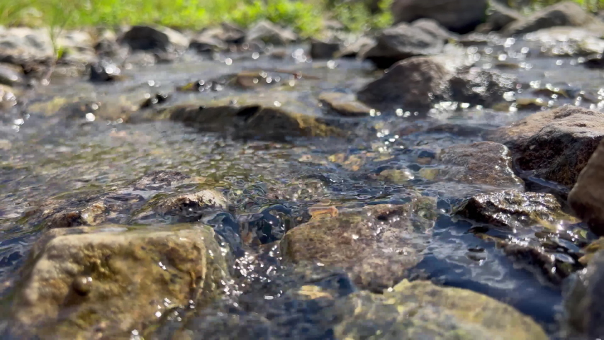Cold transparent water runs quickly through wet and smooth stones in the middle of a forest stream | Shutterstock HD Video #1096981651